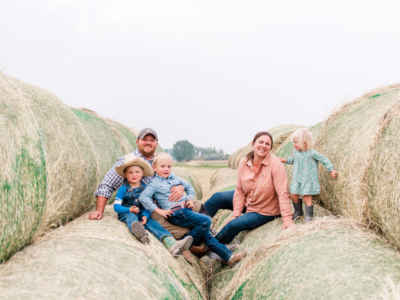 Becker family on round hay bales on stick leg ranch