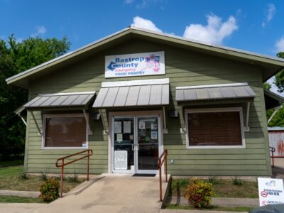 the front of a green building with a sign that says bastrop county emergency food pantry